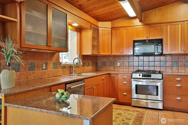 a kitchen with stainless steel appliances granite countertop a sink a stove and cabinets