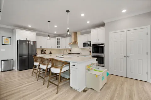 a kitchen with a sink a center island stainless steel appliances and cabinets