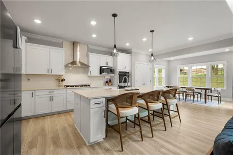 a kitchen with kitchen island granite countertop lots of white cabinets stainless steel appliances dining table and chairs