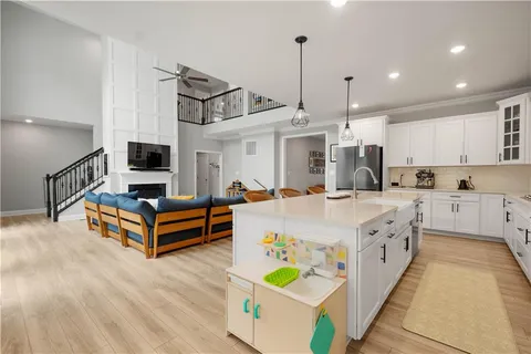 a large white kitchen with wooden floor and a sink