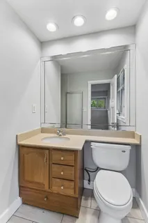 a bathroom with a granite countertop toilet sink mirror and vanity