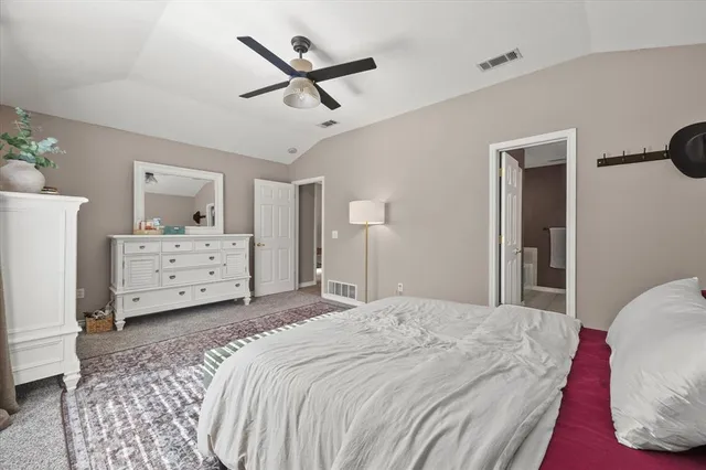 a spacious bedroom with a bed a rug and a chair