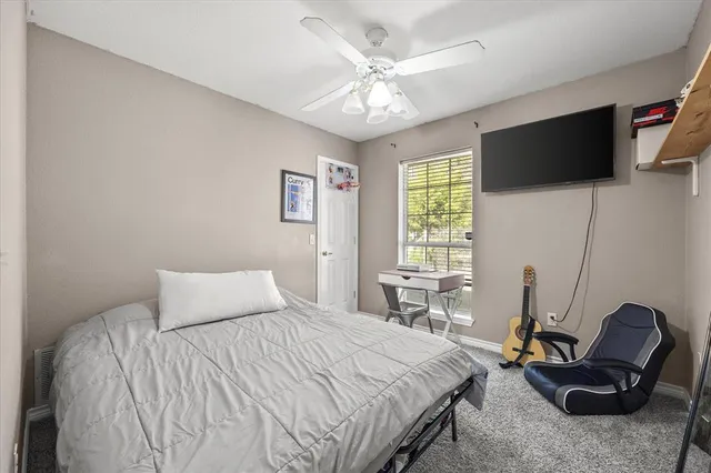 a bedroom with a bed a flat screen tv and a window