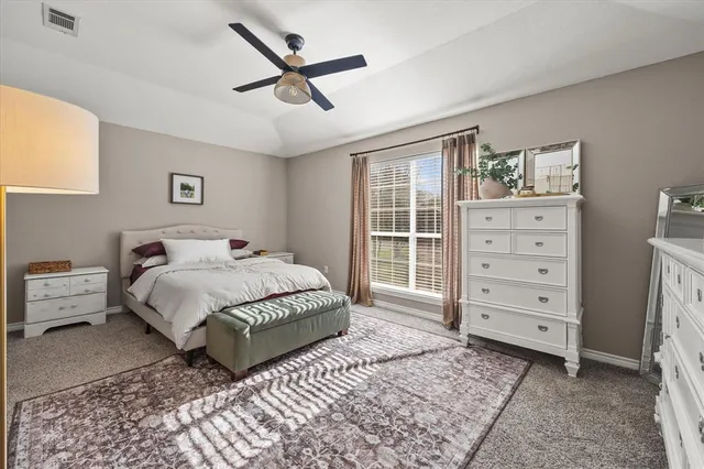 a spacious bedroom with a bed a dresser and a window