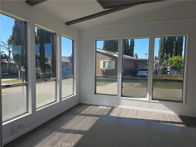 a view of empty room with floor to ceiling window and wooden floor