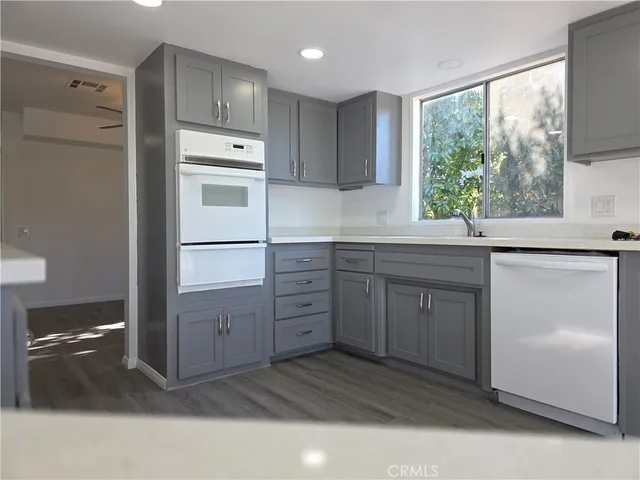 a kitchen with white cabinets and window