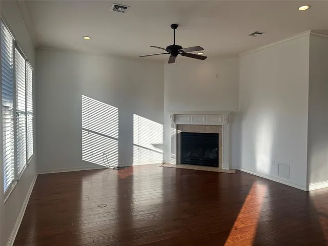a view of an empty room with wooden floor fireplace and a window