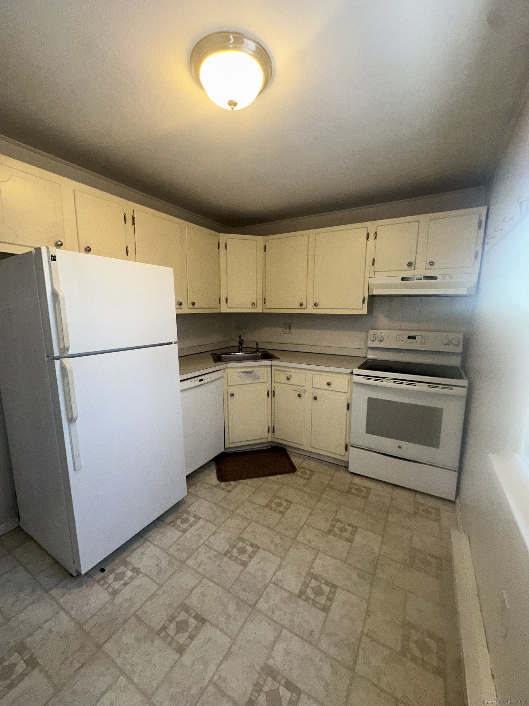 a kitchen with granite countertop a refrigerator sink stove and cabinets