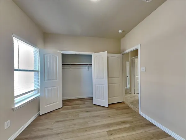 a view of empty room with wooden floor and window
