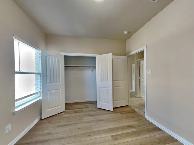 a view of empty room with wooden floor and window