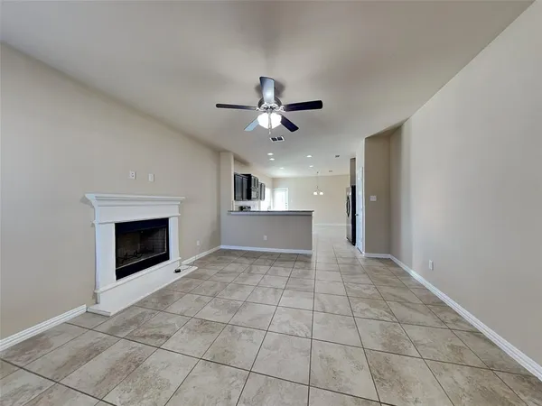a view of an empty room with kitchen and fireplace