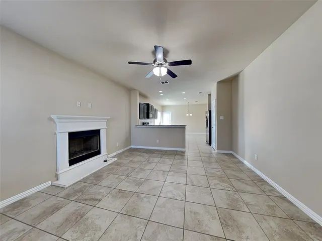 a view of an empty room with kitchen and fireplace