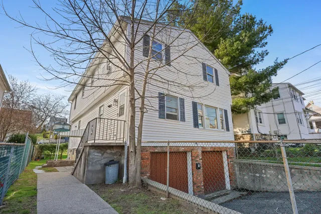 a view of a white house with a large tree