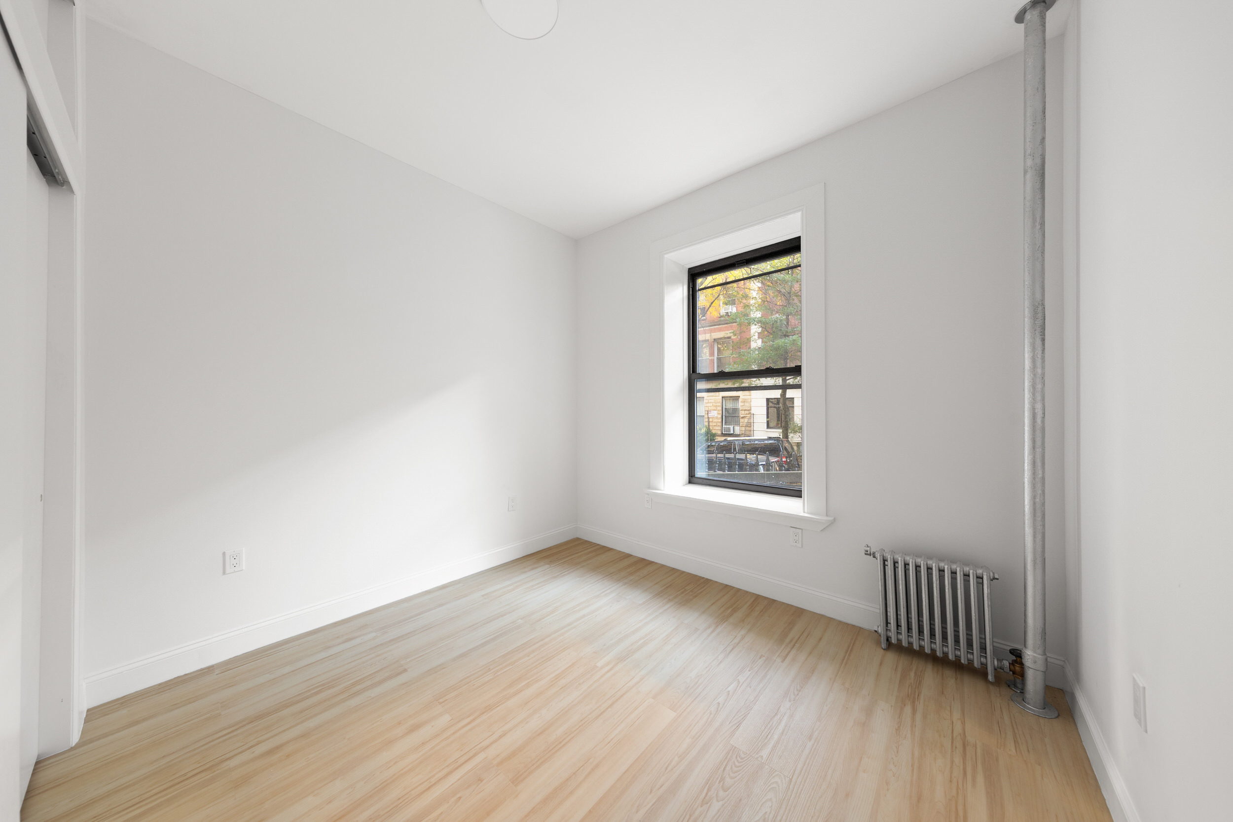 552 West 141st Street, Unit 1A Manhattan, NY 10031 - Photo 4 of 6 an empty room with wooden floor and windows