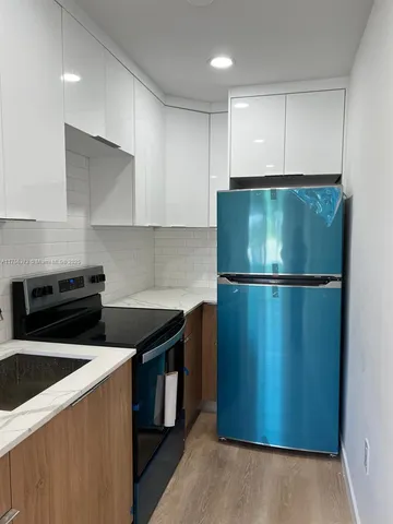 a kitchen with a refrigerator and a stove top oven