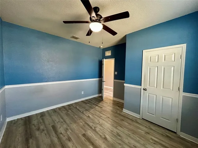 an empty room with wooden floor fan and windows