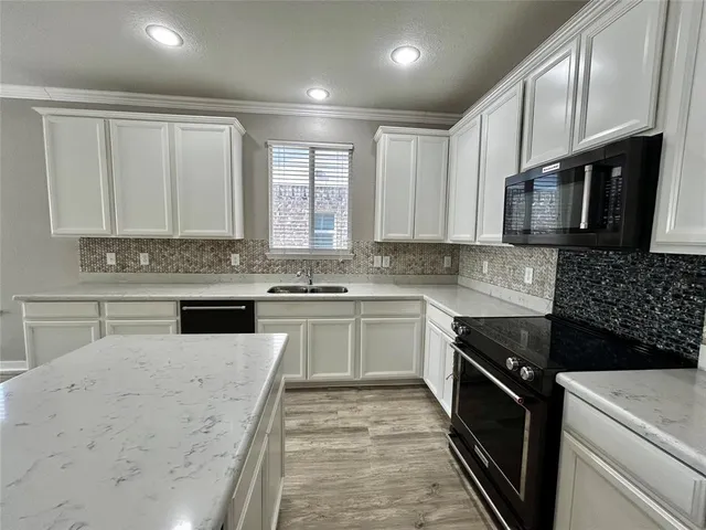 a kitchen with stainless steel appliances granite countertop a stove a sink and a microwave