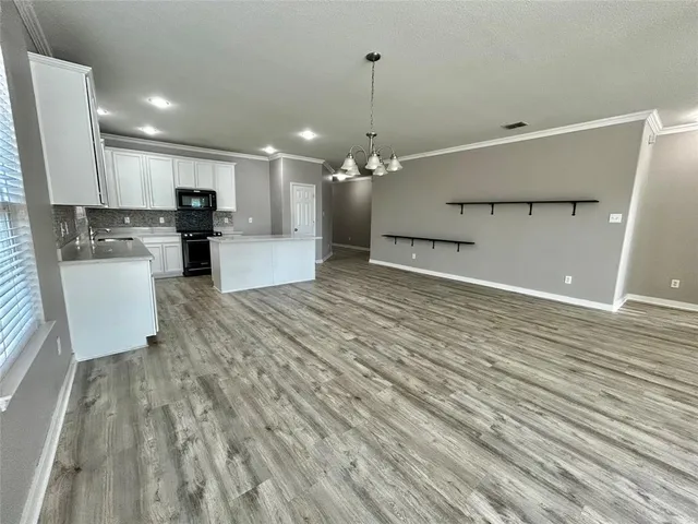 a view of a kitchen with kitchen island a sink wooden floor and a refrigerator