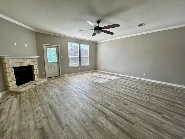 a view of an empty room with wooden floor fireplace and a window