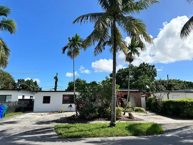 a palm tree sitting in front of a house with a yard