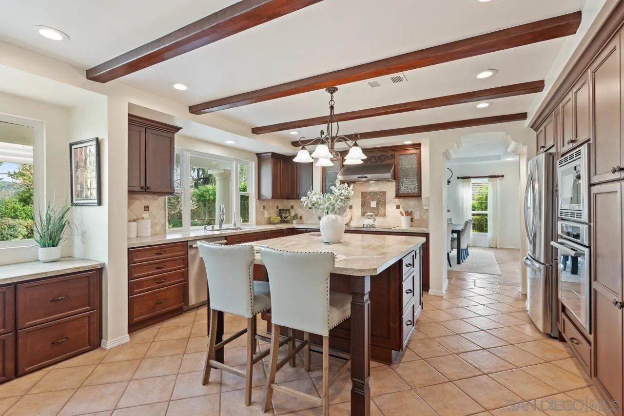 10235 Rue Chamberry San Diego, CA 92131 - Photo 22 of 72 a kitchen with stainless steel appliances kitchen island granite countertop a table chairs and a refrigerator