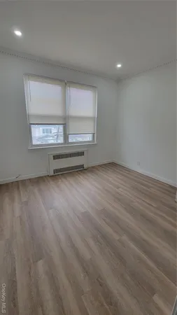 an empty room with wooden floor and window