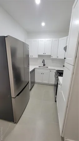 a kitchen with refrigerator and white cabinets