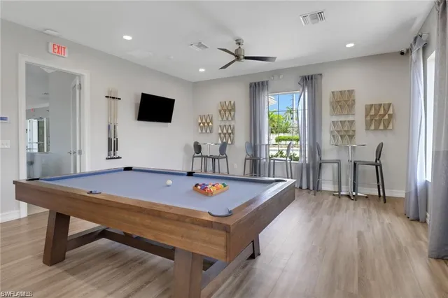 a living room with furniture pool table wooden floor and a table