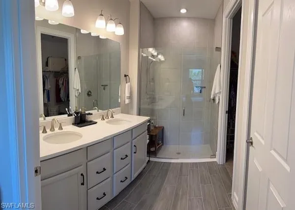 a bathroom with a double vanity sink a large mirror and shower