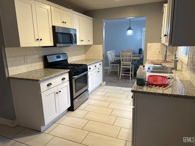 a kitchen with stainless steel appliances granite countertop a sink stove top oven and cabinets