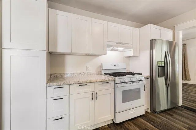 a view of a room with wooden floor staircase and a kitchen space