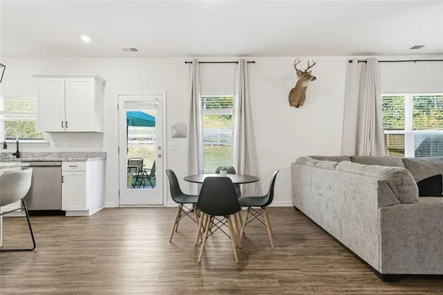 a kitchen with stainless steel appliances granite countertop a refrigerator a sink dishwasher a stove and white cabinets with wooden floor