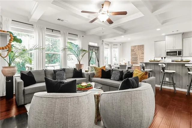 a living room with lots of furniture wooden floor and a large window