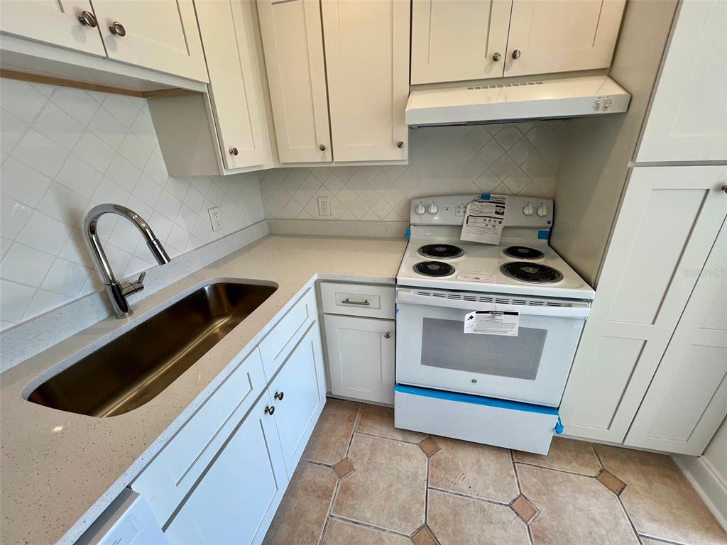 387 South McMullen Booth Road, Unit 13 Clearwater, FL 33759 - Photo 12 of 30 a kitchen with white cabinets and white appliances