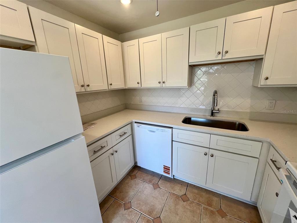 387 South McMullen Booth Road, Unit 13 Clearwater, FL 33759 - Photo 13 of 30 a kitchen with white cabinets and white appliances