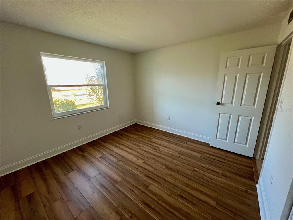 387 South McMullen Booth Road, Unit 13 Clearwater, FL 33759 - Photo 24 of 30 an empty room with wooden floor and windows