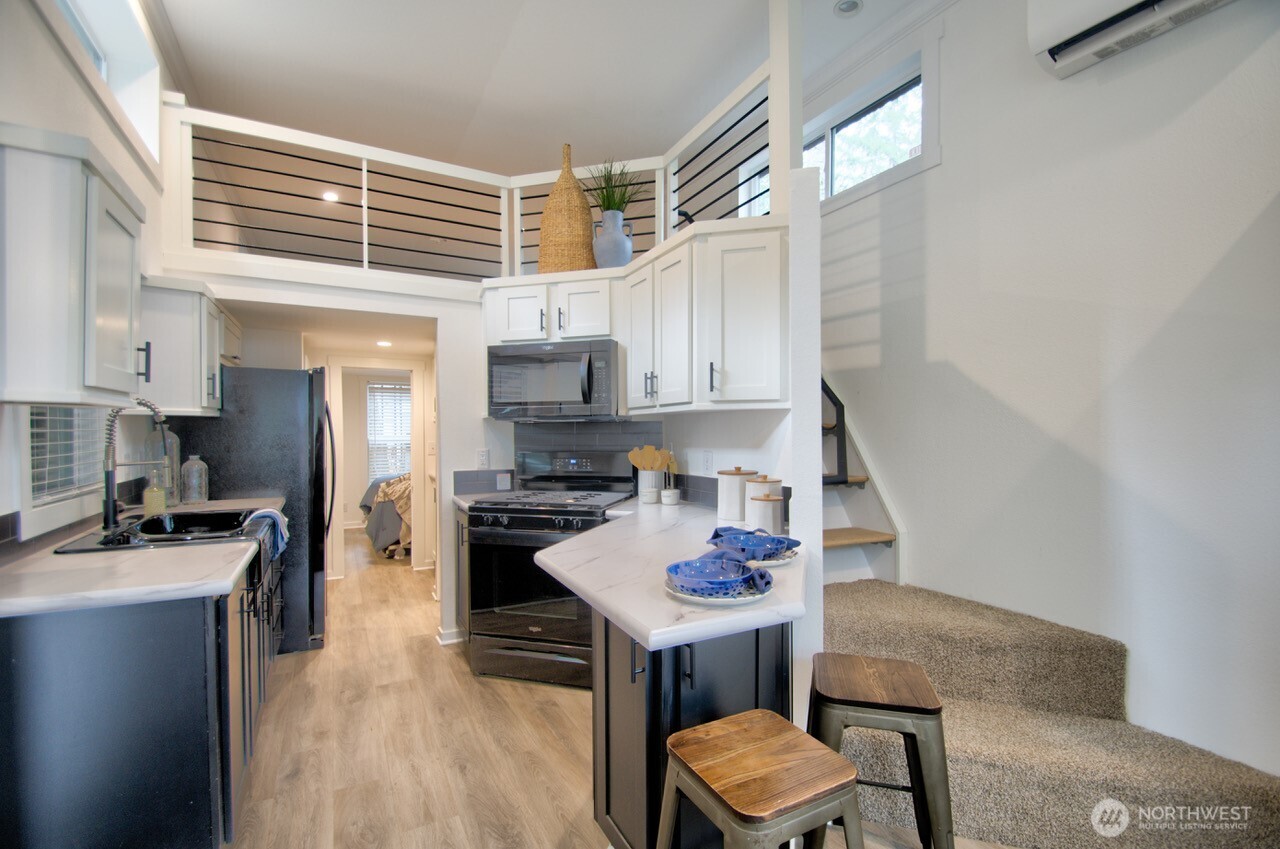 1546 Reservation Road Southeast, Unit 232 Olympia, WA 98513 - Photo 11 of 37 a kitchen with stainless steel appliances kitchen island granite countertop a stove a sink a refrigerator white cabinets and wooden floor