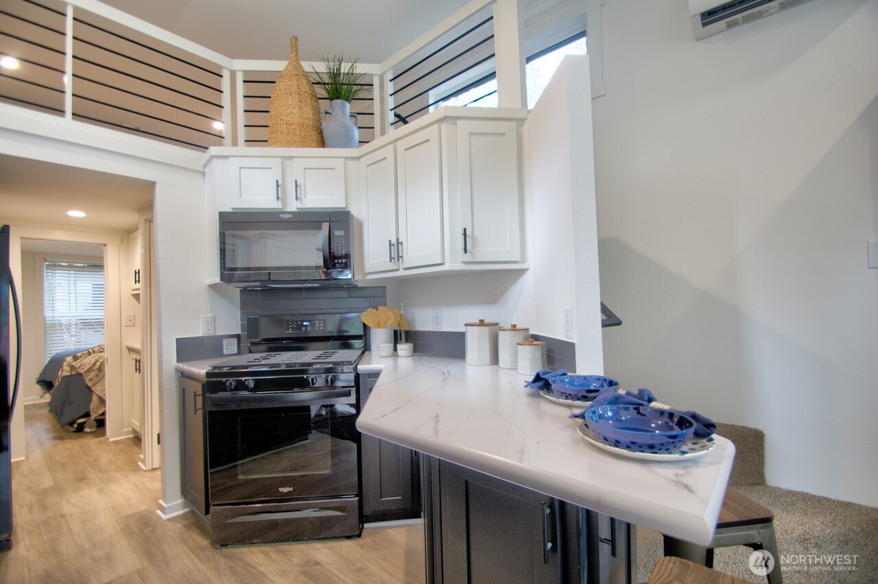 1546 Reservation Road Southeast, Unit 232 Olympia, WA 98513 - Photo 9 of 37 a kitchen with stainless steel appliances kitchen island granite countertop a sink a stove and a microwave