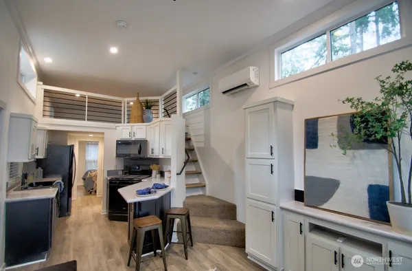 a kitchen with stainless steel appliances kitchen island granite countertop a stove a sink a refrigerator white cabinets and wooden floor