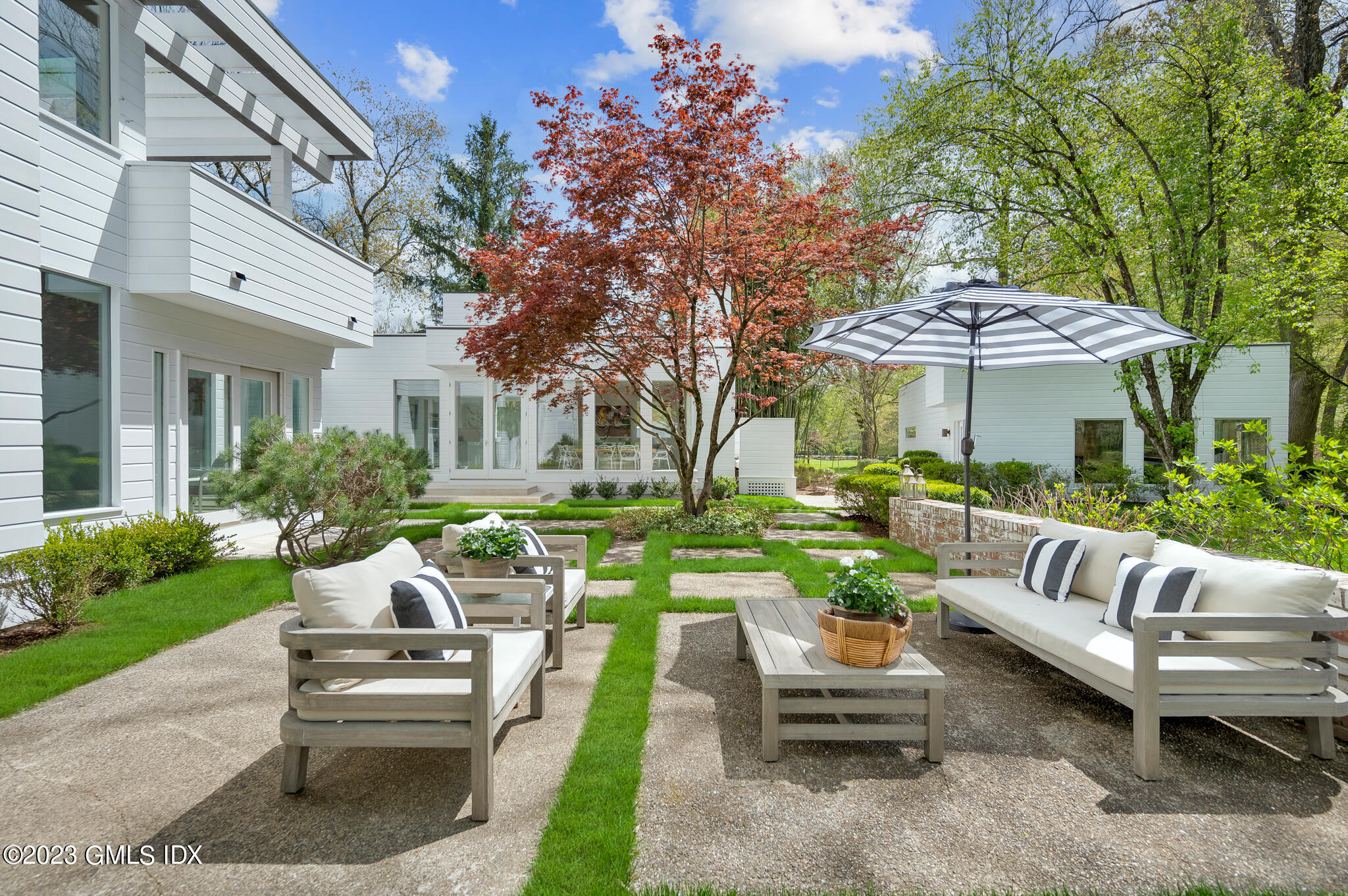 294 Riversville Road Greenwich, CT 06831 - Photo 14 of 17 a view of a patio with couches table and chairs under an umbrella with a garden