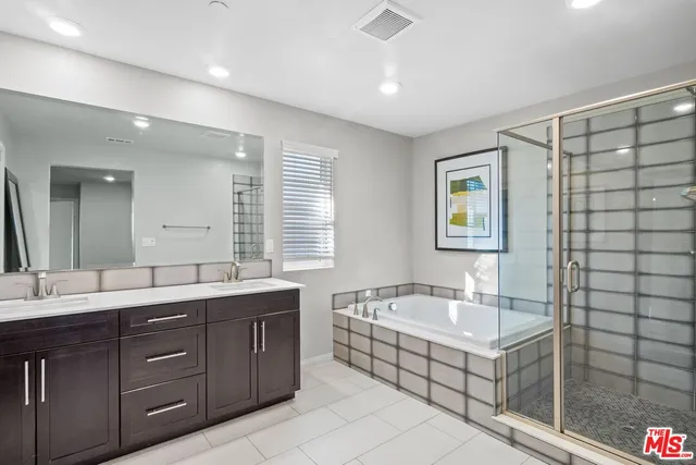 a bathroom with a tub sink double vanity granite and a mirror