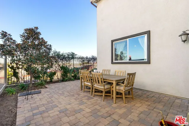 a patio with a table and chairs and potted plants