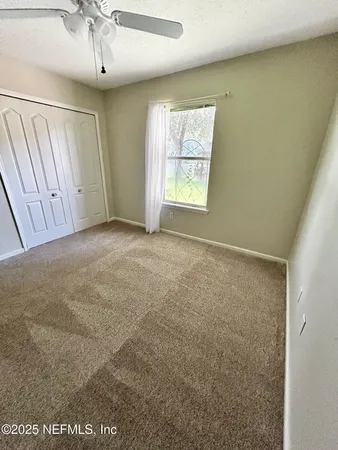 an empty room with windows and fan