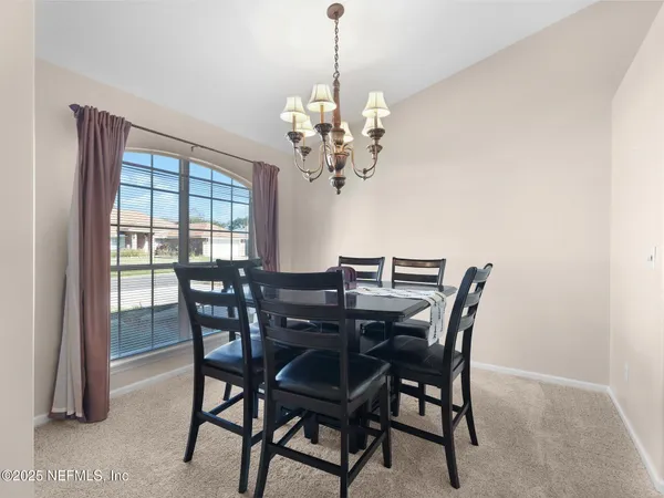 a view of a dining room with furniture a chandelier and window