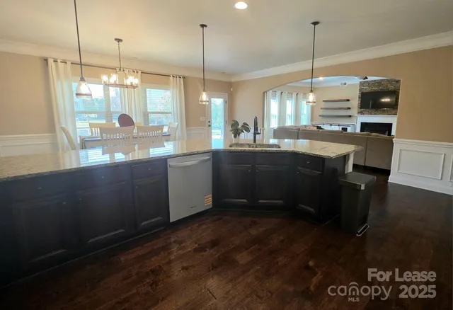 a open kitchen with stainless steel appliances granite countertop a stove a sink dishwasher and a wooden floor