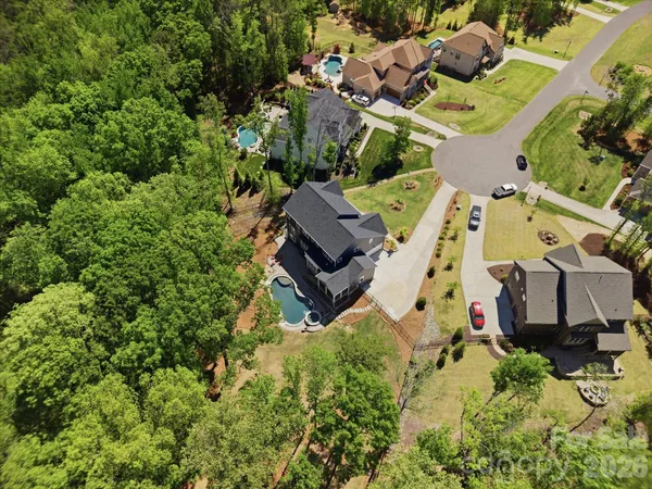 a view of a big yard with swimming pool and lawn chairs