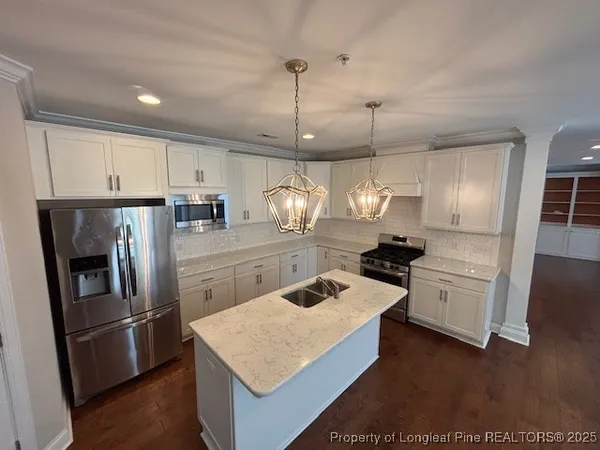 a kitchen with a refrigerator a sink dishwasher and a stove with wooden floor