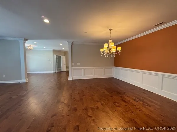 a view of a room with wooden floor chandelier and a window