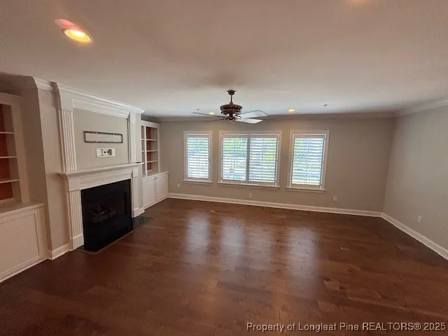an empty room with windows fireplace and wooden floor