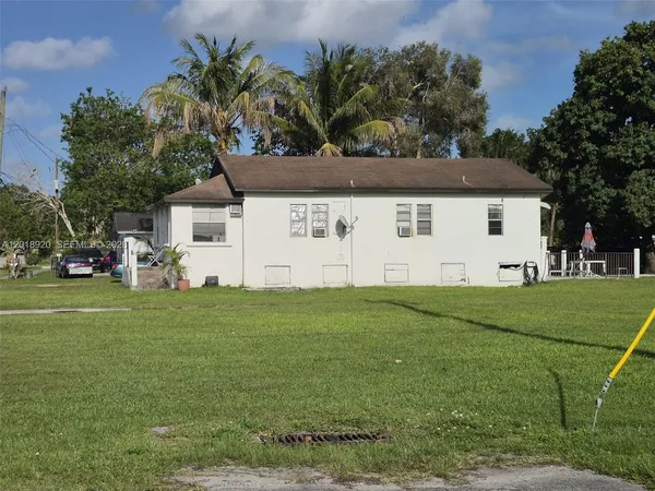 a view of a white house with a big yard and large trees